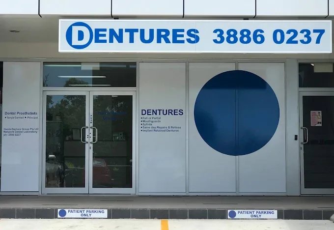 North Lakes Denture Care entrance with blue Dentures sign, glass entry doors and patient parking bays in front